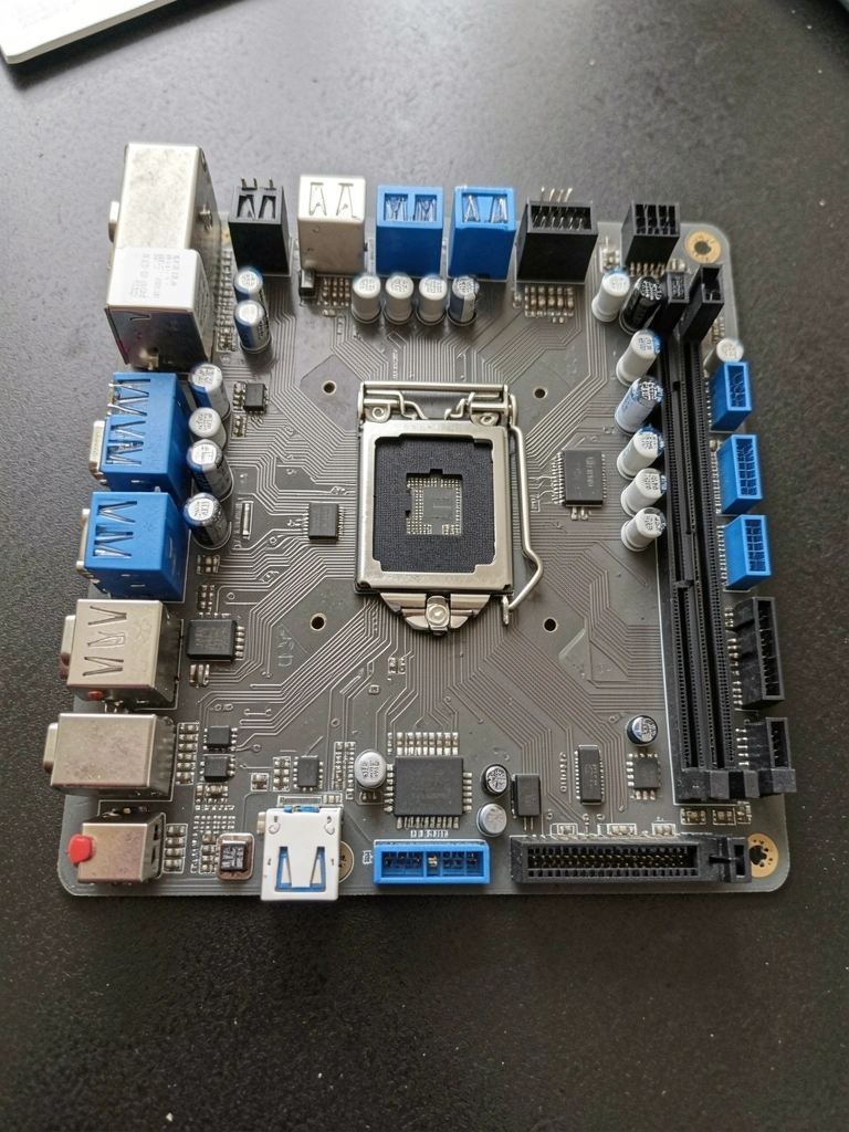 Placa-mãe Asus Prime H410M-E sobre mesa de madeira clara, com processador e memórias RAM instalados, iluminação ambiente suave.