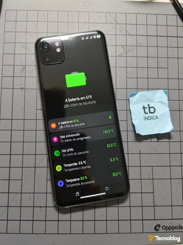 Celular robusto apoiado em superfície de madeira, com tela ligada exibindo ícones coloridos, bateria de 7000mAh em destaque no texto da tela