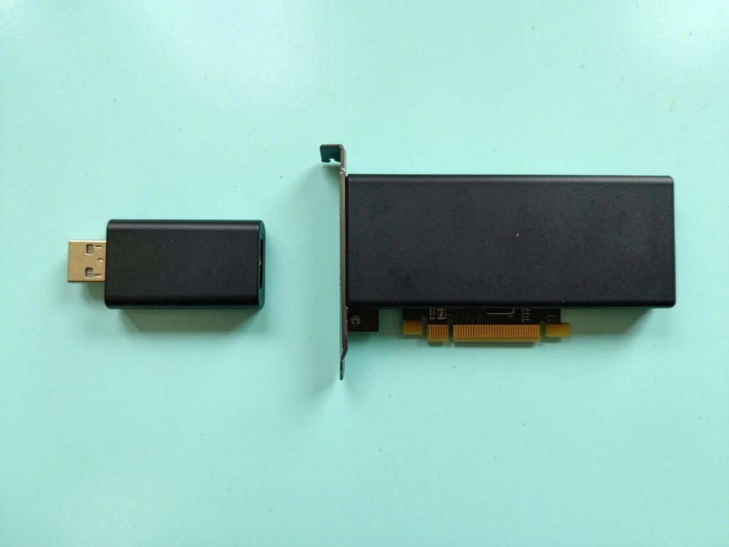 Dongle USB e placa PCIe lado a lado sobre superfície cinza.