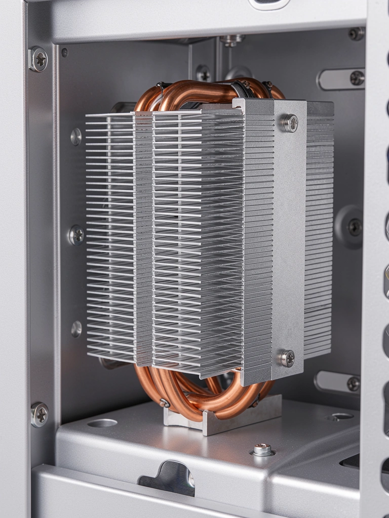 Dissipador de alumínio com heat pipes de cobre montado em gabinete prateado, parafuso visível na lateral, reflexo sutil da iluminação de estúdio.