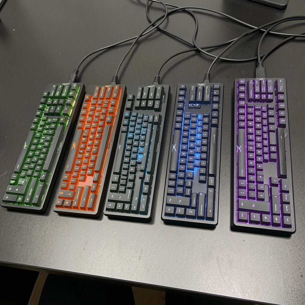 Cinco teclados HyperX Alloy alinhados em uma bancada, cada um com iluminação RGB distinta.